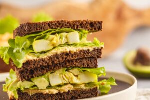 Bocadillo vegano con hummus, aguacate y espinacas frescas
