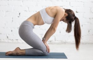 Mujer hace una postura de yoga para mejorar la hinchazon abdominal y dolor lumbar