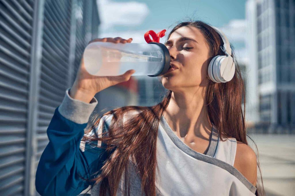 Mujer bebe agua después de hacer deporte