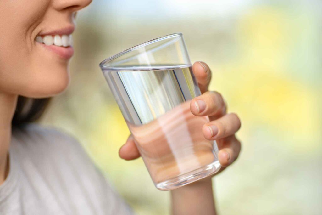 Mujer sonriente bebe un vaso de agua