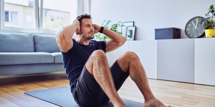 Hombre hace sit-ups en casa