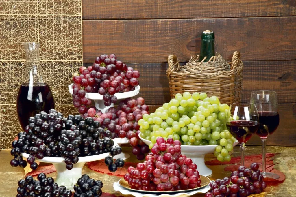 uvas de diferentes colores en una mesa acompañadas de vino